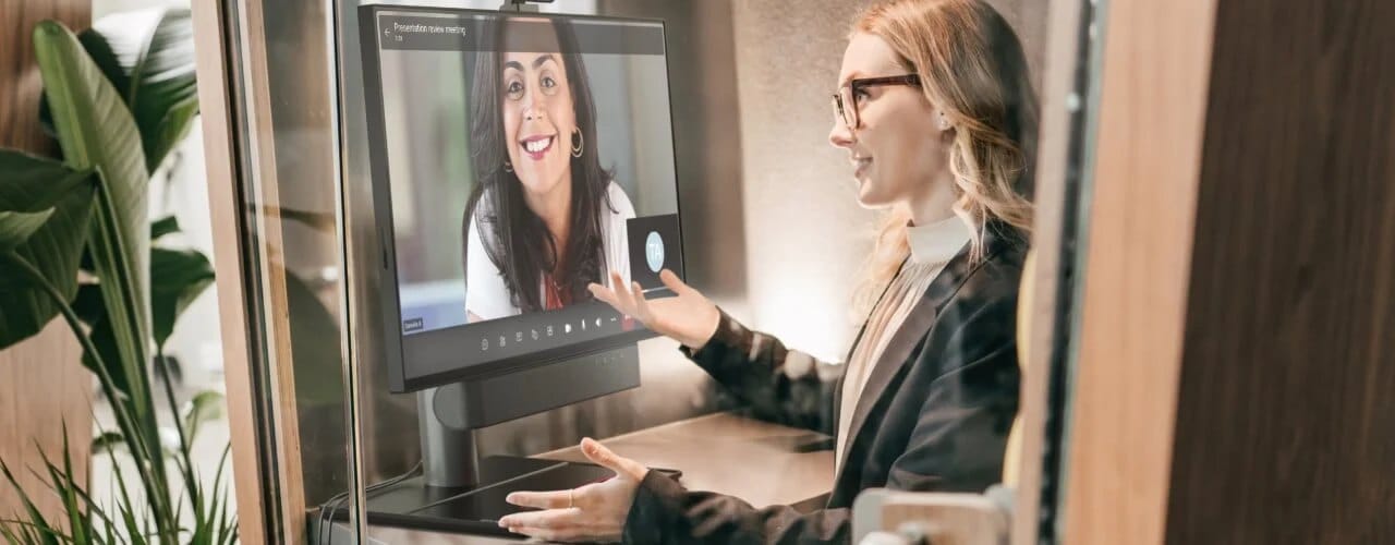 ThinkSmart View Plus with web camera and sound bar sitting in front of a woman speaking on a conference call in a private conference room