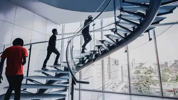 Three people walking up a modern spiral staircase