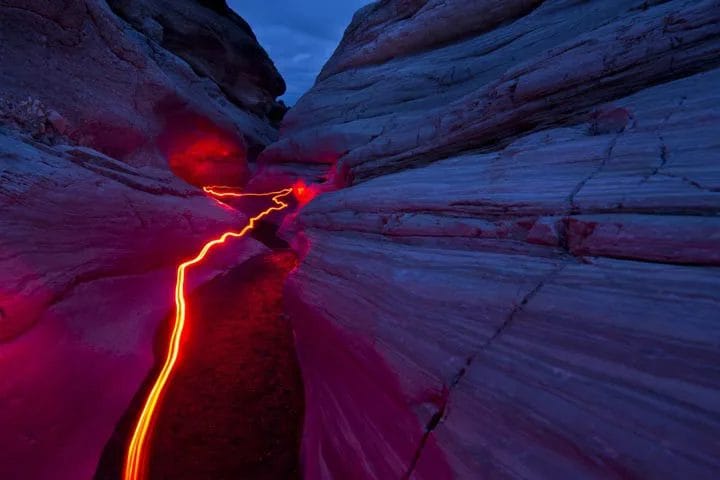 A red stream of light moving through a canyon