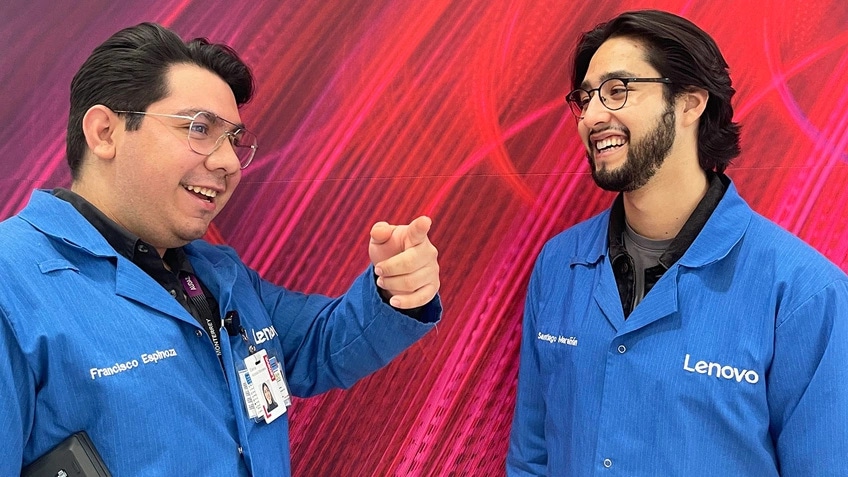 Two people standing with laptops