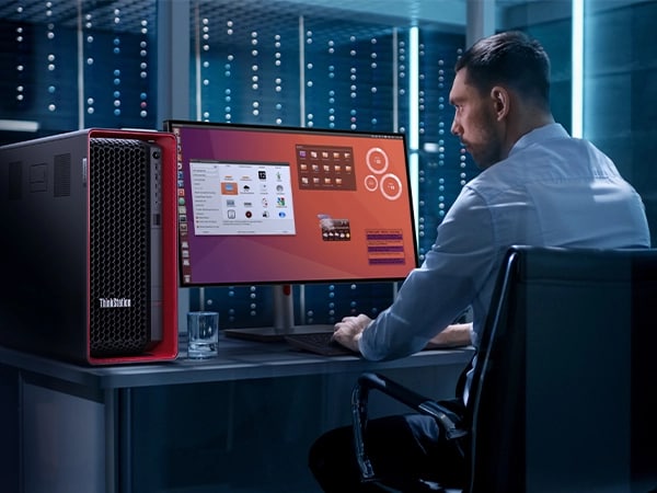 Data scientist looking at multiple apps on a large monitor, typing on a keyboard, with Lenovo ThinkStation P7 workstation to the left