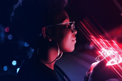 A person holding a string of lights that is shining red light onto her face