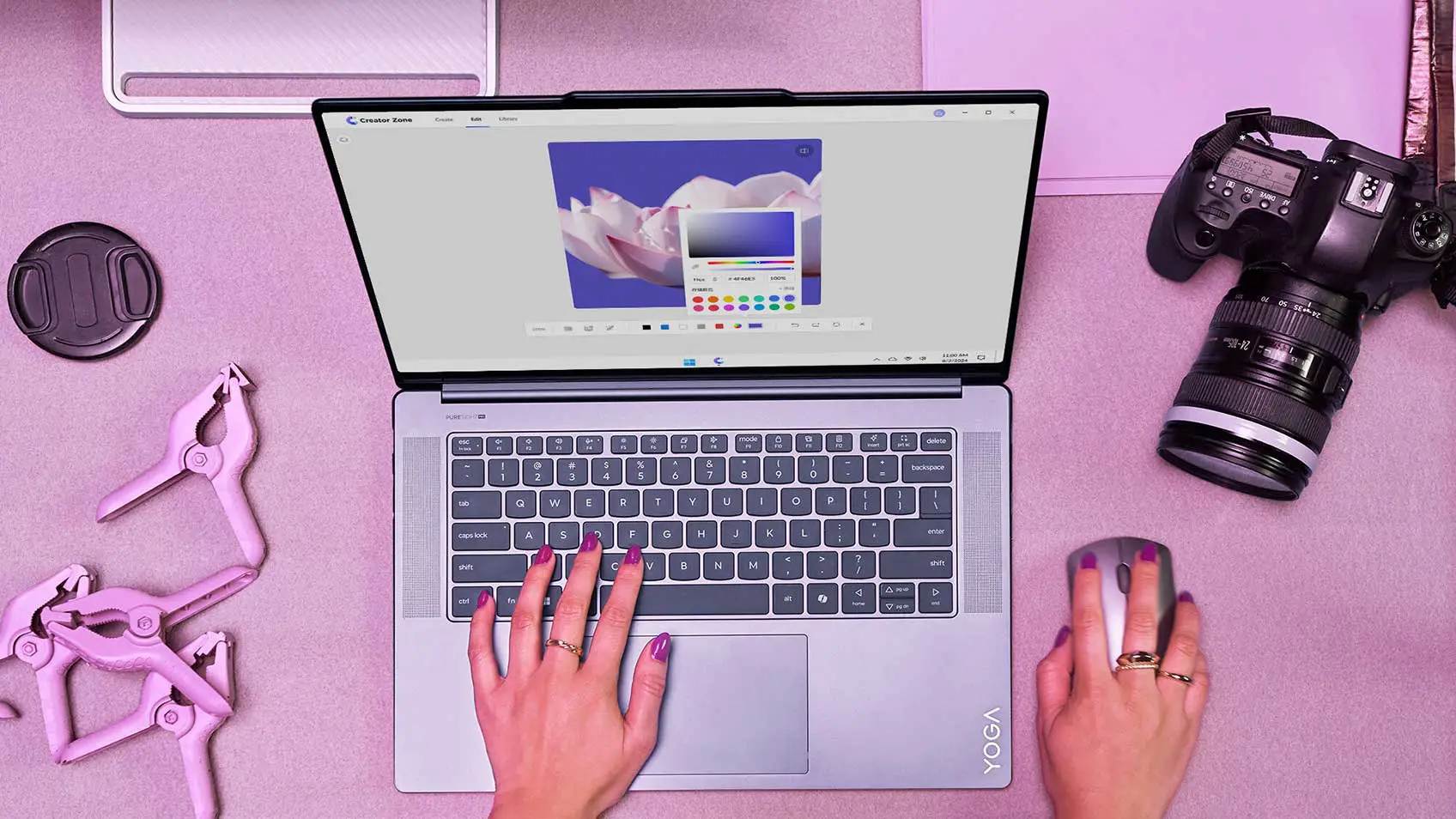 A photographer’s laptop open on her pink desk next to her camera