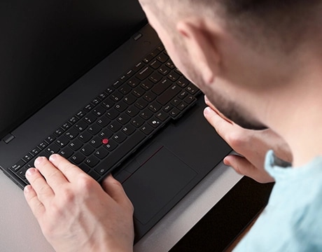 Over-the-left-shoulder view of a person with their hands on the keyboard of a Lenovo ThinkPad L16 Gen 2 (16" Intel) laptop
