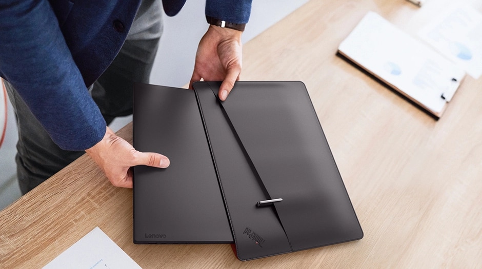 A man slips the ThinkPad X13 Gen 6 (13” AMD) into a folio case above a desk.