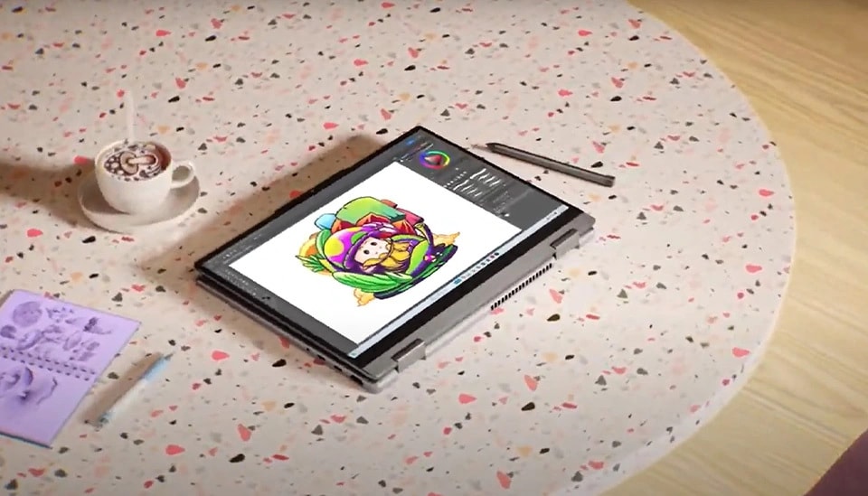 Un portable IdeaPad 2 en 1 repose sur une table à côté d’une tasse de café, d’un stylet numérique et d’un petit ordinateur portable.