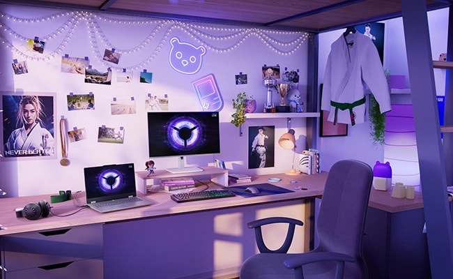 Lenovo LOQ Essential 15IRX11 gaming laptop on a desk with mouse, keyboard, mousepad, and monitor – left-front view, lid open, with LOQ logo in purple on the display and on the monitor screen.
