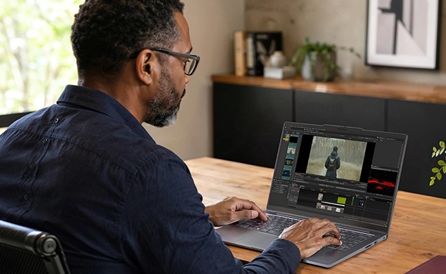 A man at a desk working on video editing software on the Lenovo ThinkBook 14 Gen 9 (14&Prime; Snapdragon) laptop.