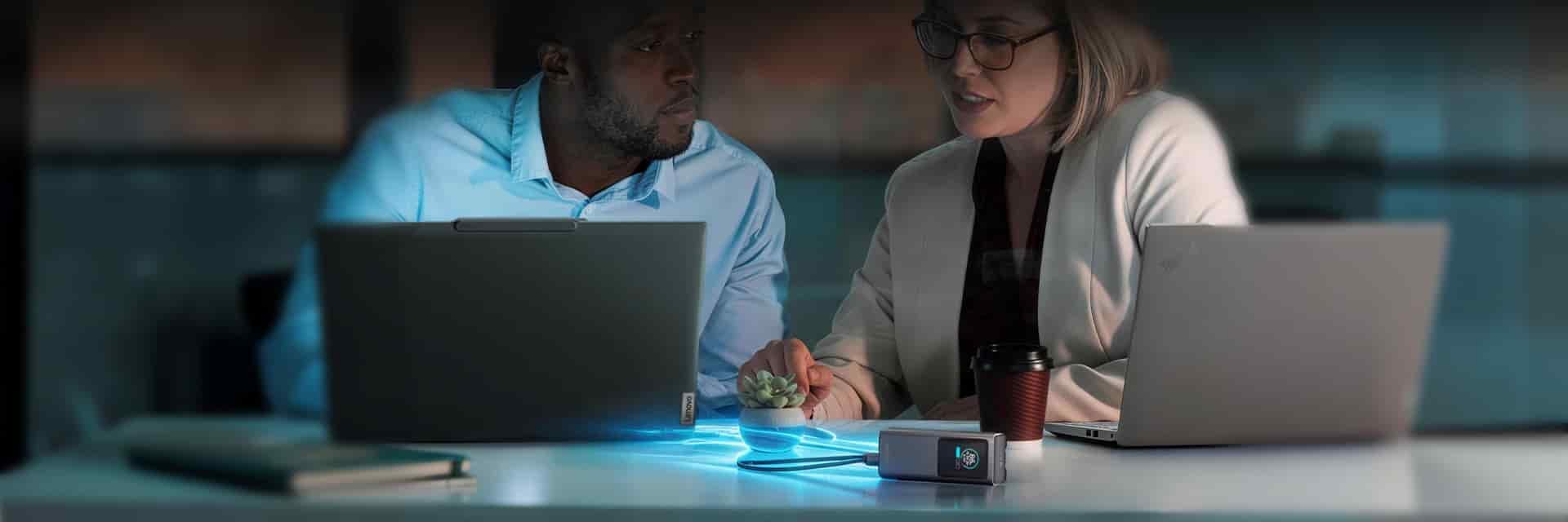 A power bank charging two laptops in a shared workspace.
