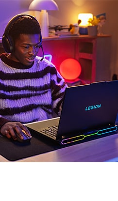 A gamer is fully immersed in gameplay on a Lenovo Legion Pro laptop, using a Legion wireless gaming mouse and wearing a Legion wireless gaming headset.