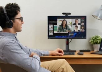 Un homme d’affaires habillé de façon décontractée se contente de s’asseoir comme son bureau et de parler virtuellement à l’assistance Lenovo Pro sur son écran ThinkVision.