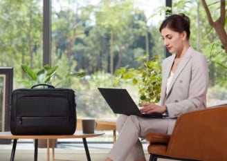 Une femme d’affaires bien habillée lisant du contenu à l’aide d’un Lenovo ThinkPad X1 Carbon dans son bureau brillamment éclairé.
