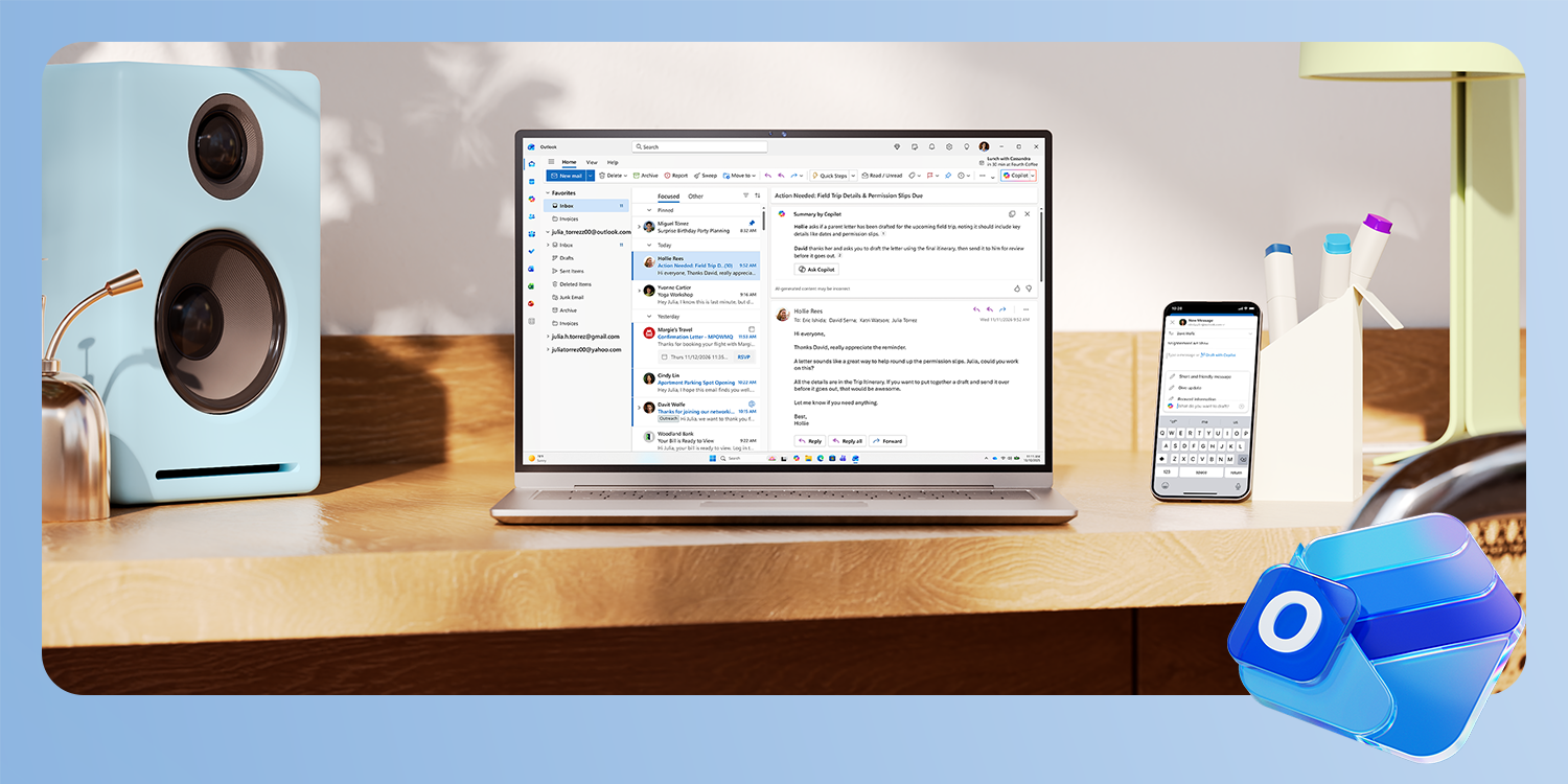 Lenovo laptop on a wooden desk displaying the Microsoft Outlook email interface, with a smartphone, desk organizer, and a blue speaker visible in the background. Outlook Icon in the bottom right corner