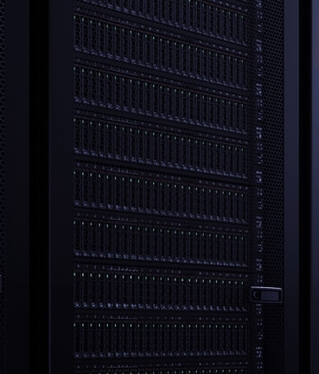 Two coworkers with laptops and tablets walking through a server room