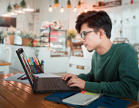 Designer editing images in a cozy cafe using the Lenovo ThinkPad P16s i Gen 5 (Intel) mobile workstation for creative tasks.