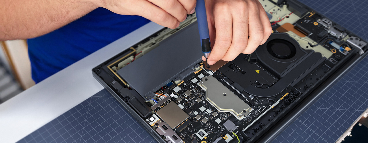 A pair of hands use a tool on the opened bottom of the Lenovo ThinkPad T15 Gen 5 (16” Intel) laptop.