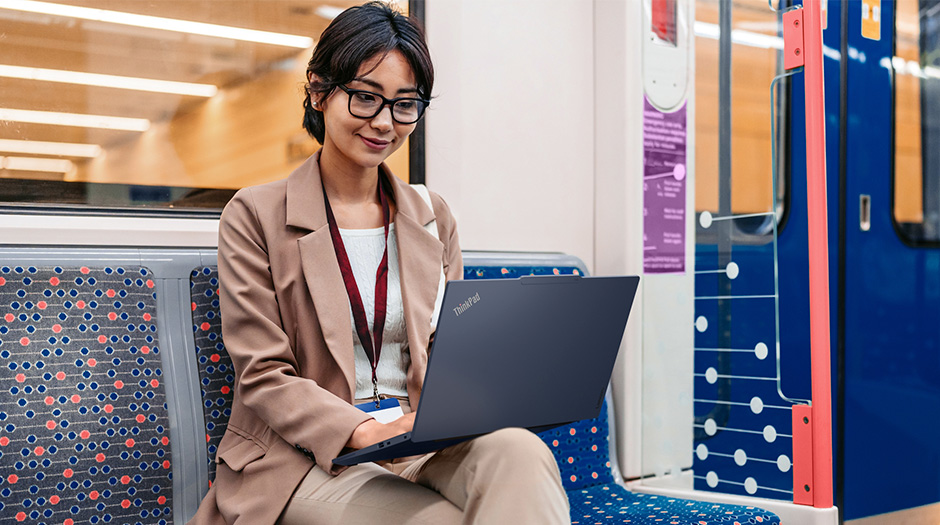 一名女性在公共交通工具上使用 Cosmic Blue 顏色的 Lenovo ThinkPad T14s Gen 7 (14” Intel) 筆記型電腦打字。