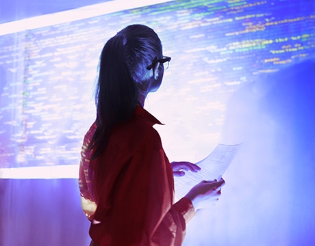 Woman analyzes data projected on a screen, highlighting advanced tech use.