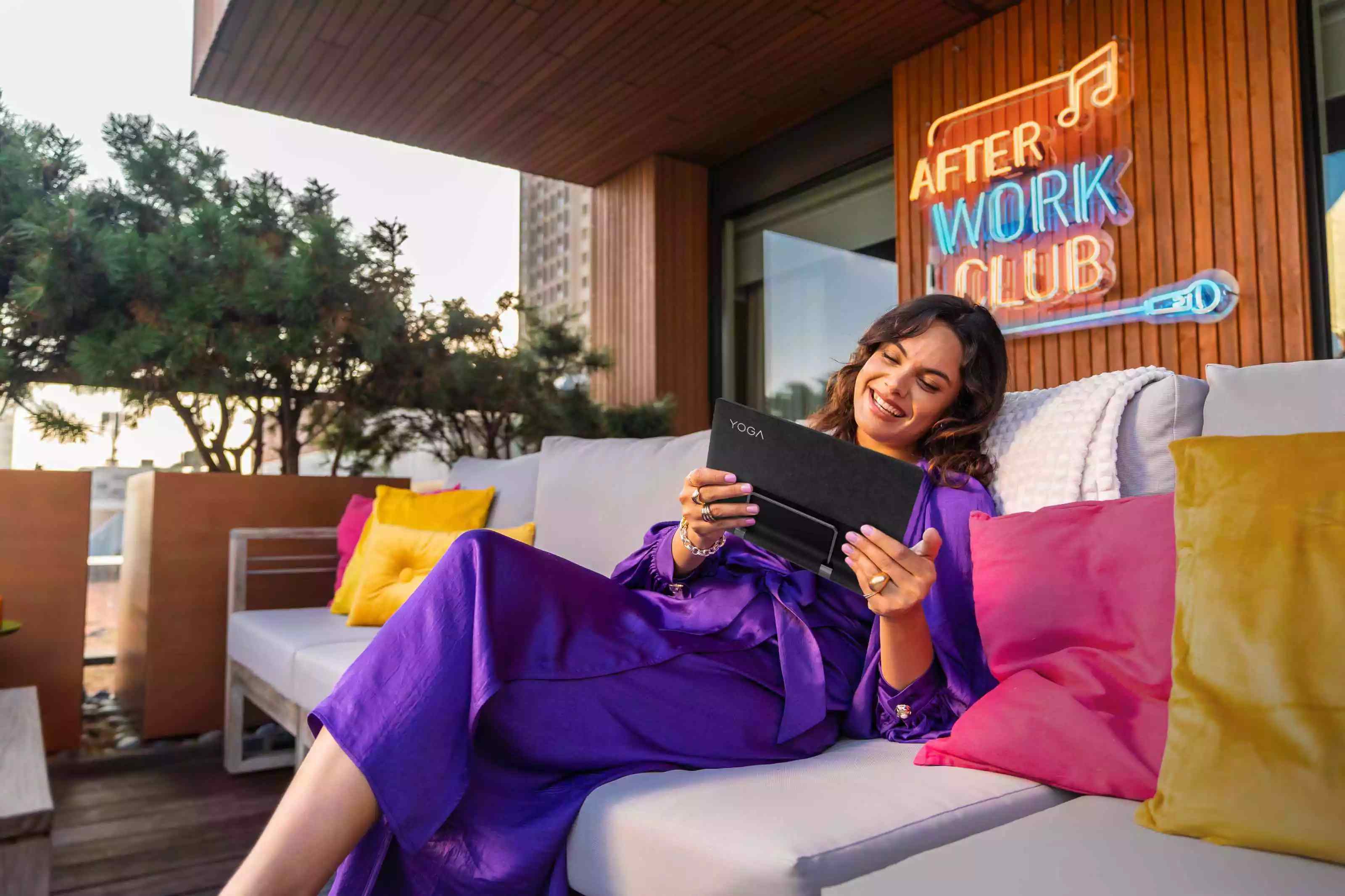 Woman relaxing on her outdoor couch, enjoying viewing content on her Lenovo Tablet.