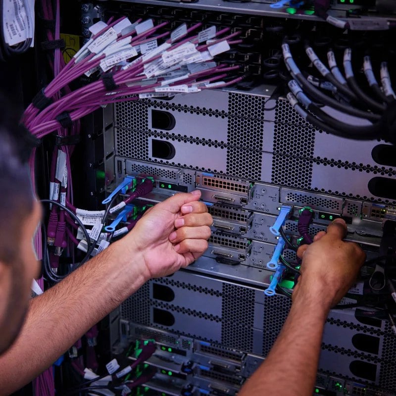 Vue arrière d'un rack de stockage de serveurs Lenovo avec un technicien inspectant le centre du rack de stockage