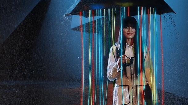 Personne sous la pluie avec un parapluie. Des rubans de bannières de couleurs mutilées sont suspendus.