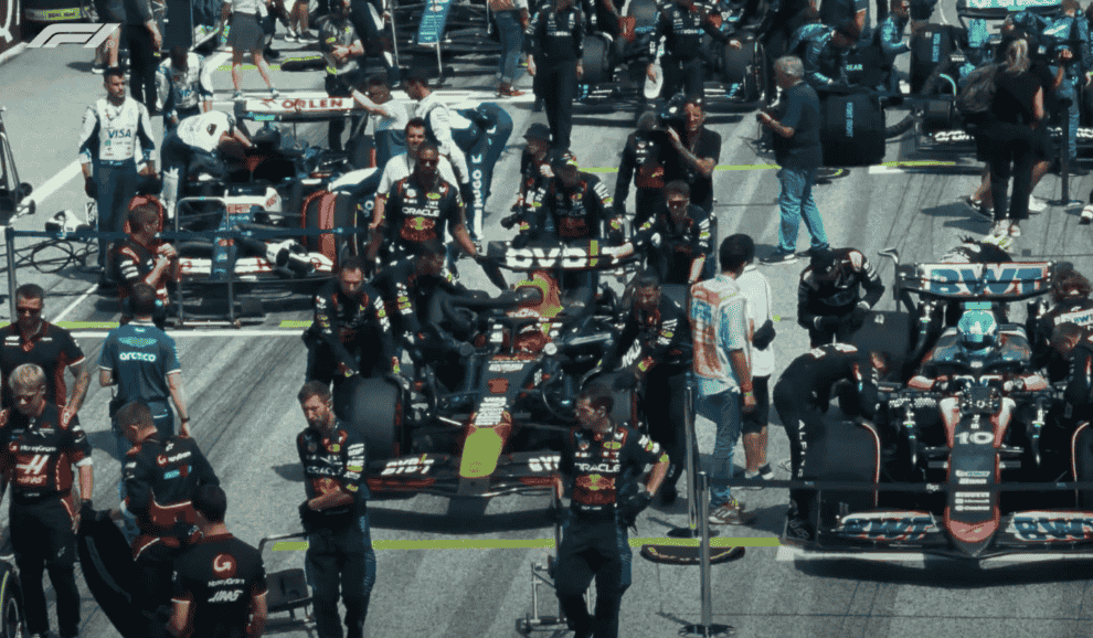 Une image d’un groupe de pilotes de course F1 debout à côté de leurs voitures de course.