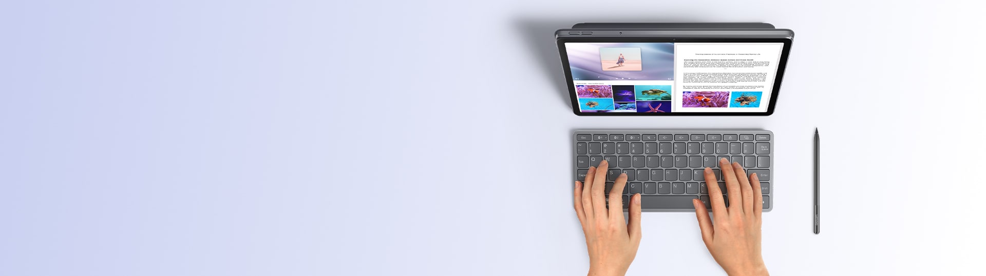 Top view of a user typing on a Lenovo tablet with a bluetooth keyboard and stylus placed beside the device.