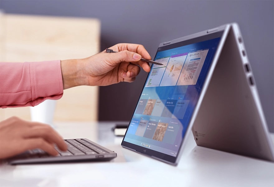 Portable Lenovo ThinkPad X1 Yoga Gen 8 2 en 1 en mode tente à côté d’un clavier sans fil, utilisé avec le stylet intégré.
