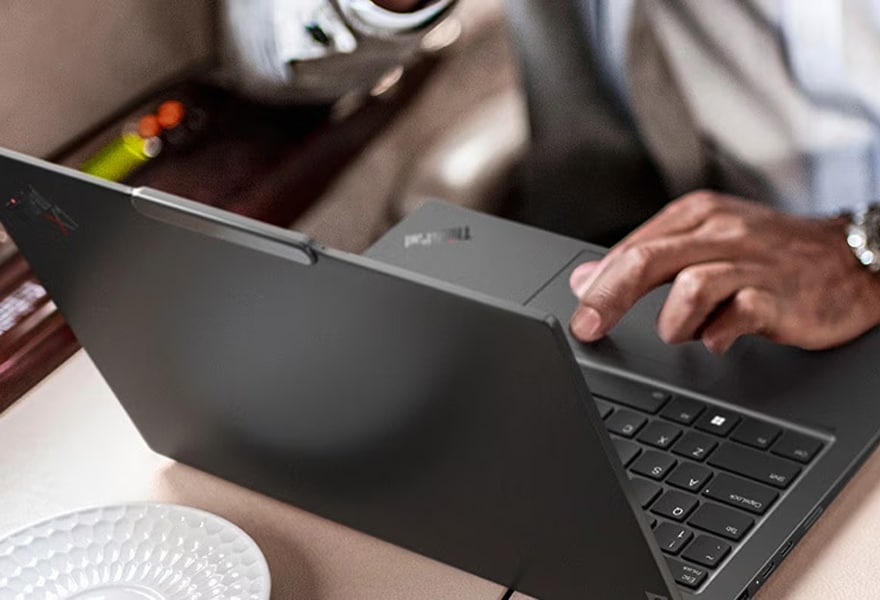 Eine Person trägt ein ultraportables Lenovo ThinkPad X1 Carbon Gen 12 Notebook unter dem Arm