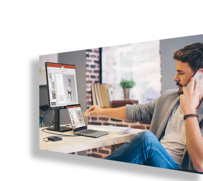 Young man looking at Lenovo laptop and secondary monitor, showing a chair