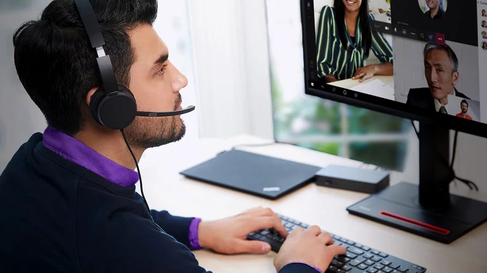 Person wearing Lenovo headset using Lenovo Workstation displaying online meeting