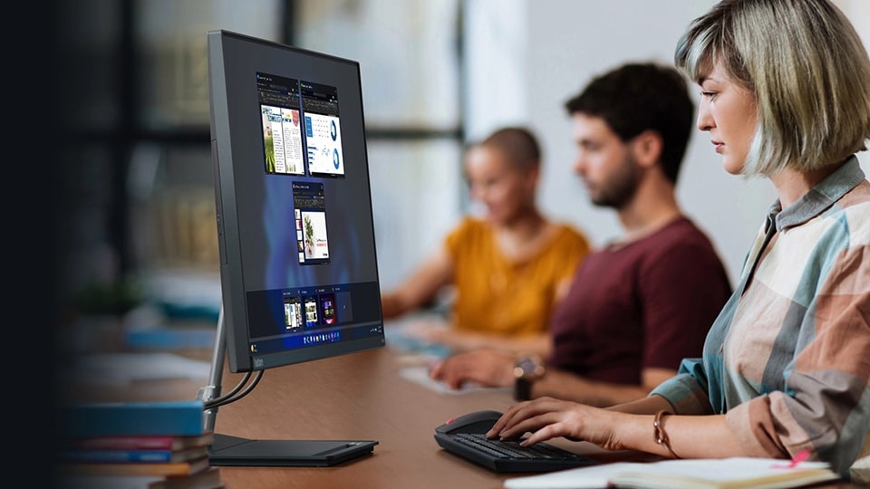 Een moderne kantooromgeving met een Lenovo ThinkCentre Neo 30a op een bureau, met iemand die op een toetsenbord typt