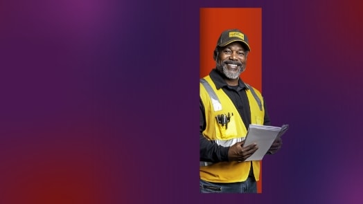 Smiling man in safety vest holding papers on orange background.