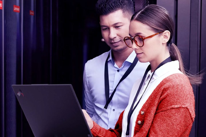 Image of two IT techs working together on a laptop.