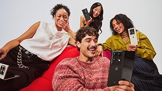 Three motorola razr fold phones, one with its display opened up, stand atop a reflective surface.