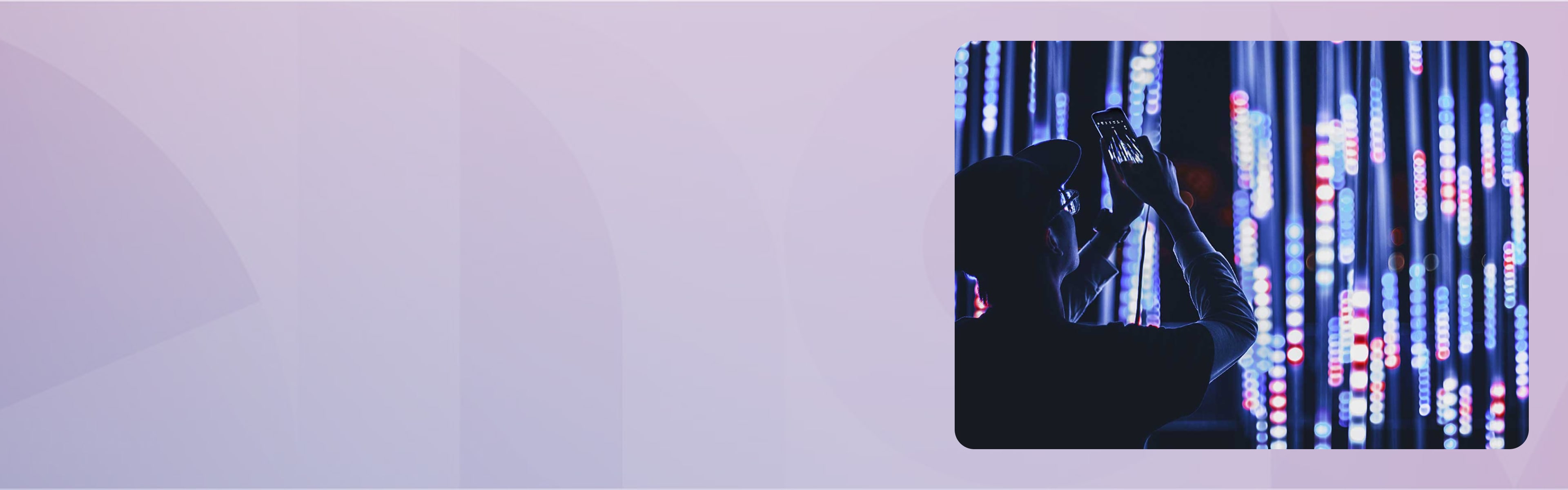 A man holding up his phone to take a picture of blue lights.