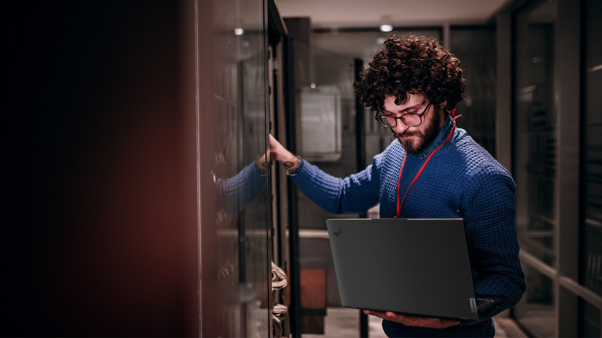 A man holding a laptop in a server room.