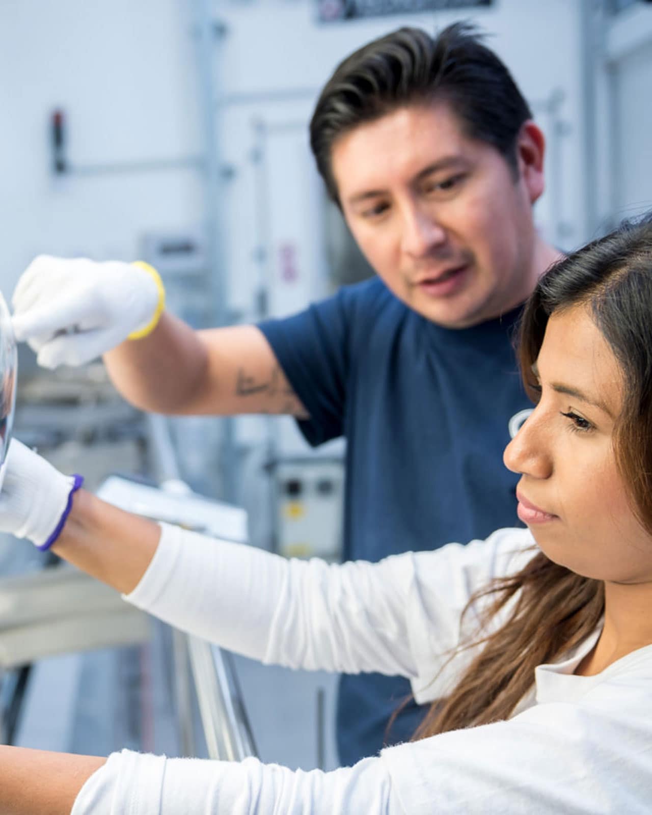 Two colleagues wearing white gloves working in a lab 