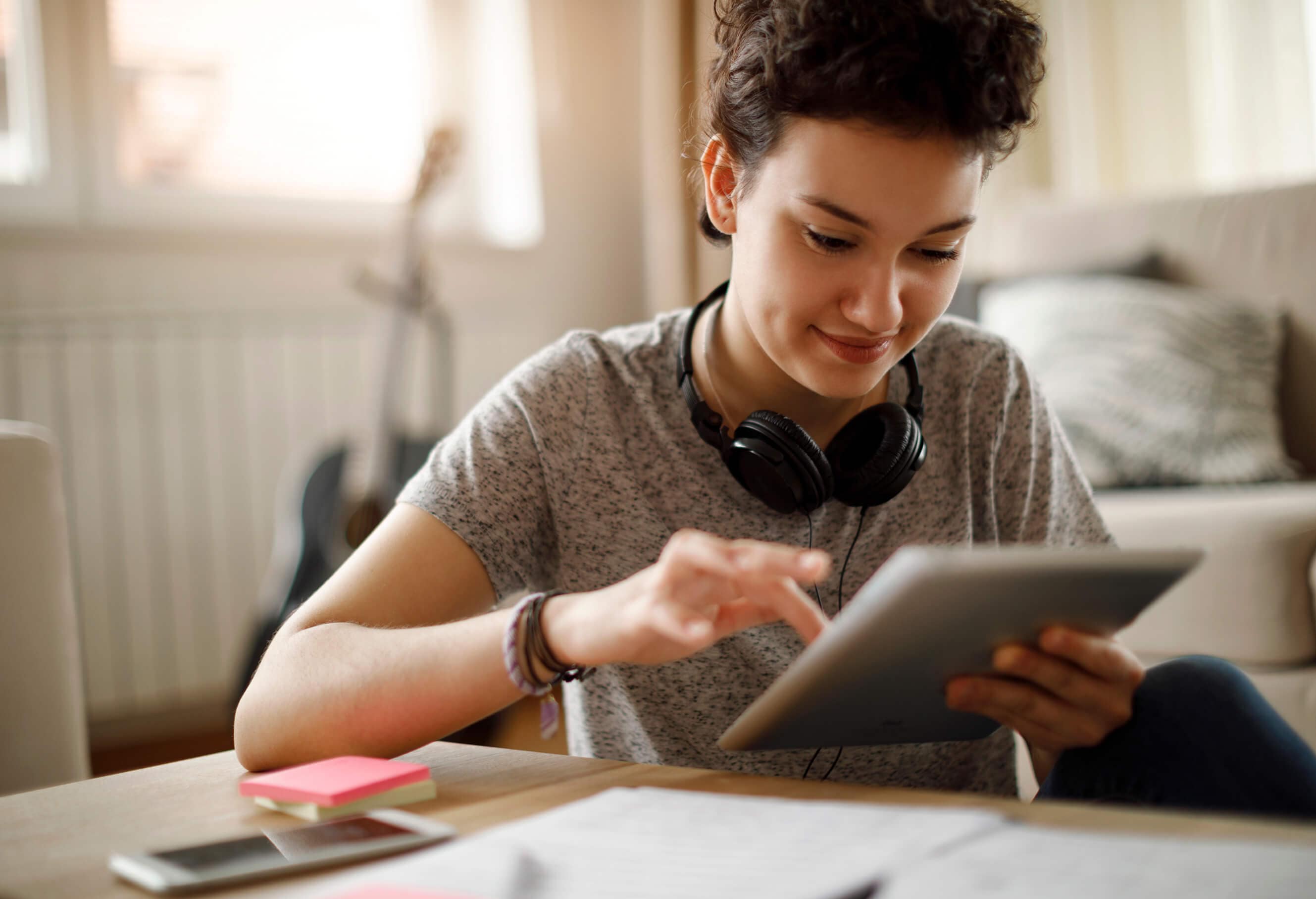 ヘッドホンを首にかけ、タブレットを使うクリエイター。