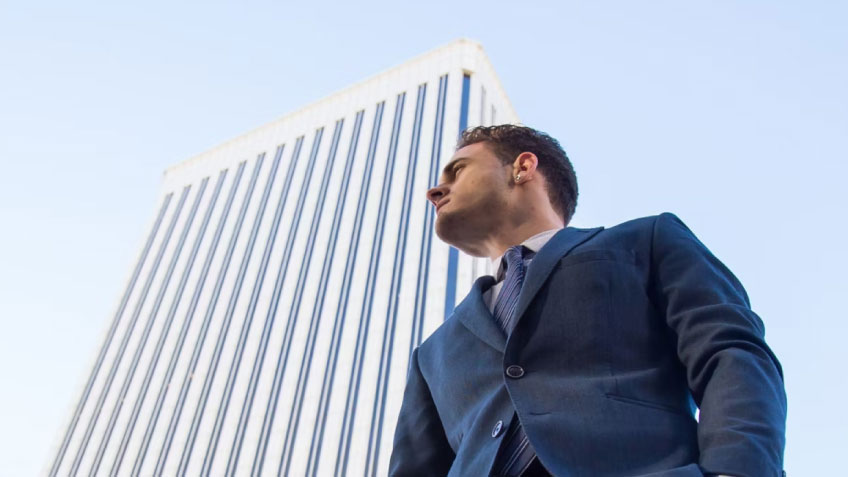Image of a businessman standing in front of a tall building.