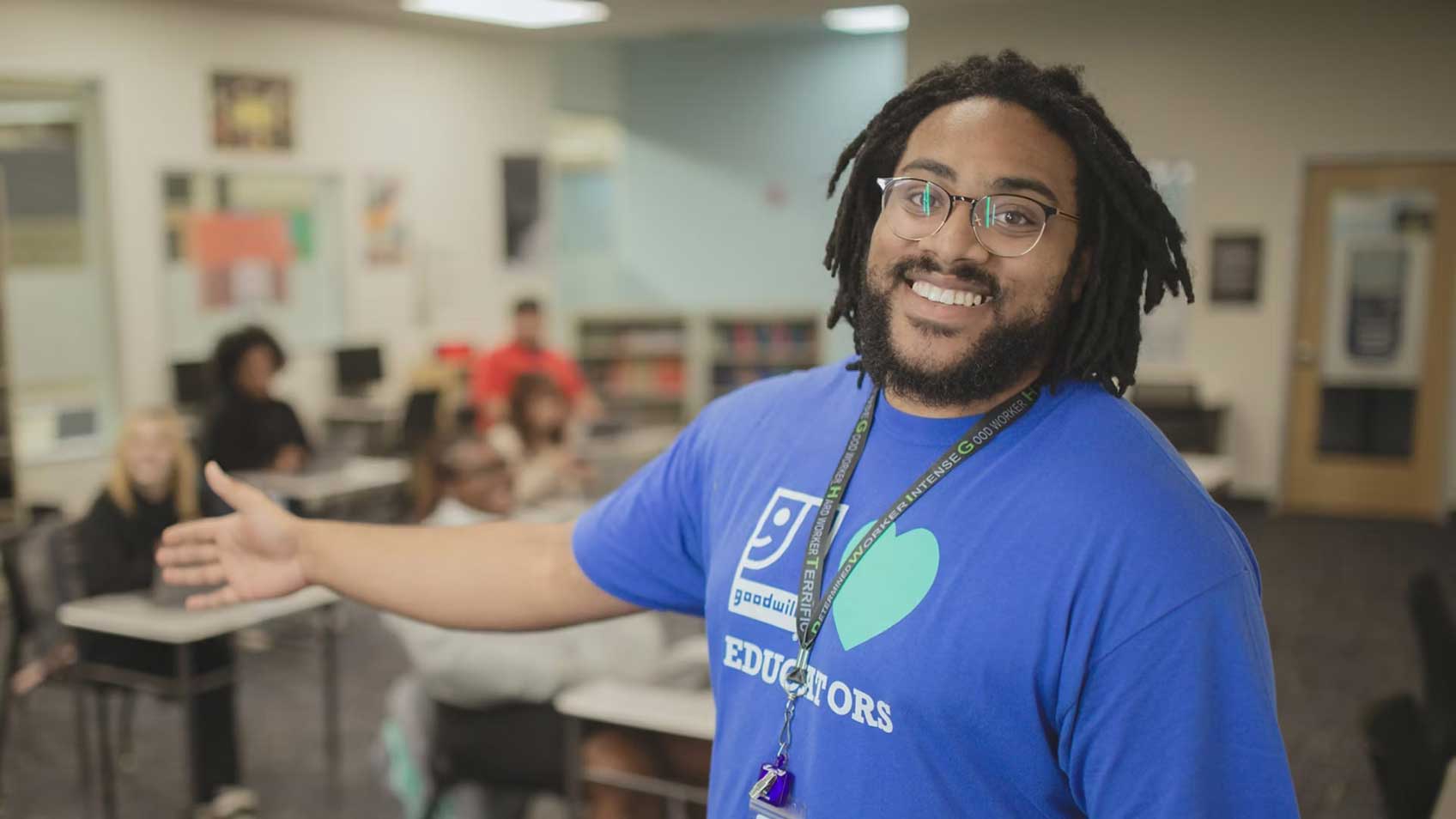Un empleado de Goodwill sonriendo con el personal de oficina detrás de él. 