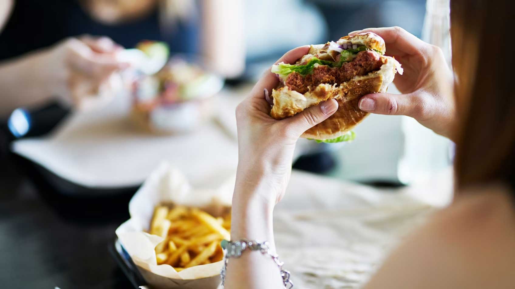 Dos manos que sostienen una hamburguesa para comer. 