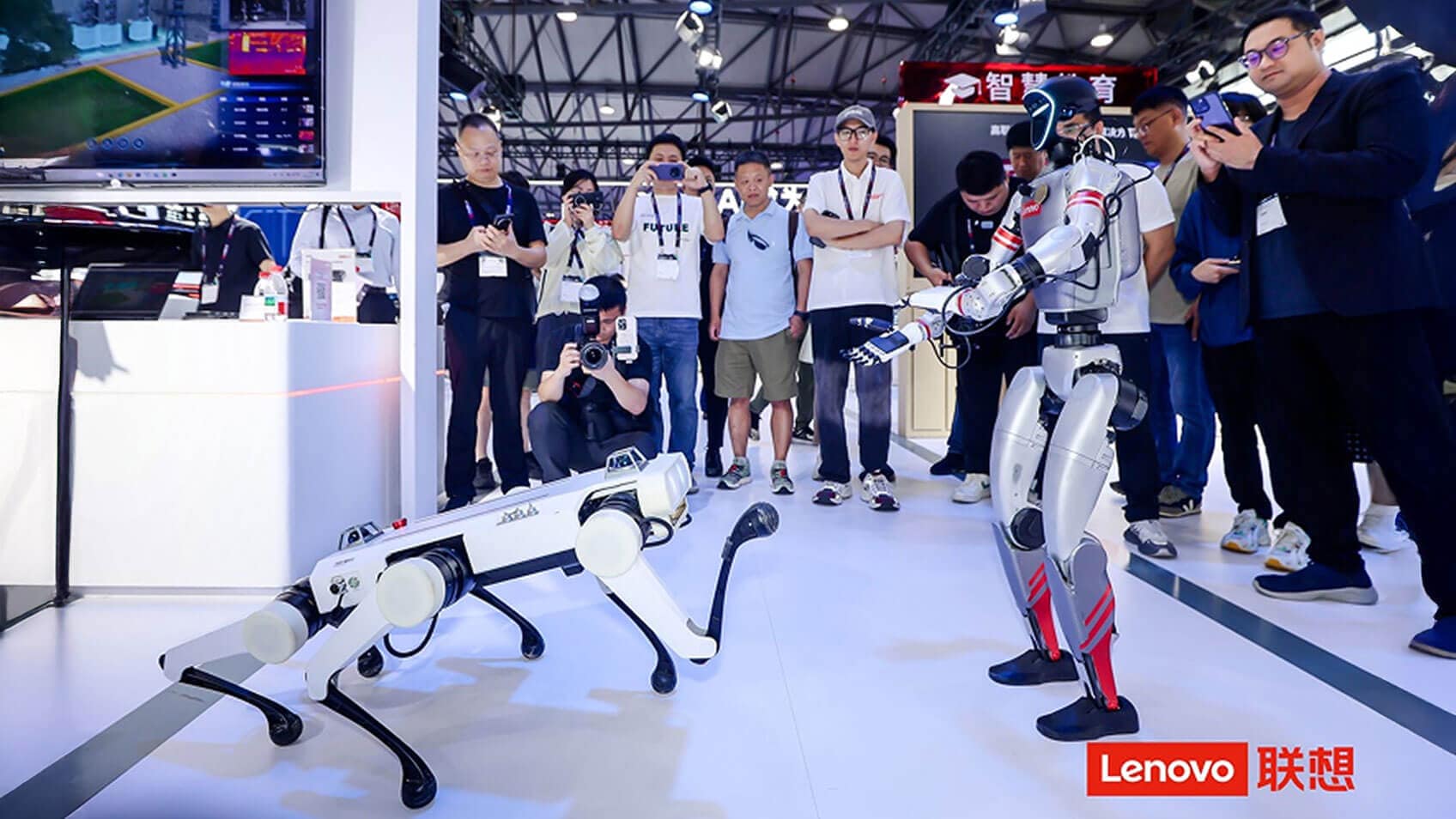 Onlookers watching a human-like robot interact with a six-legged robot. 