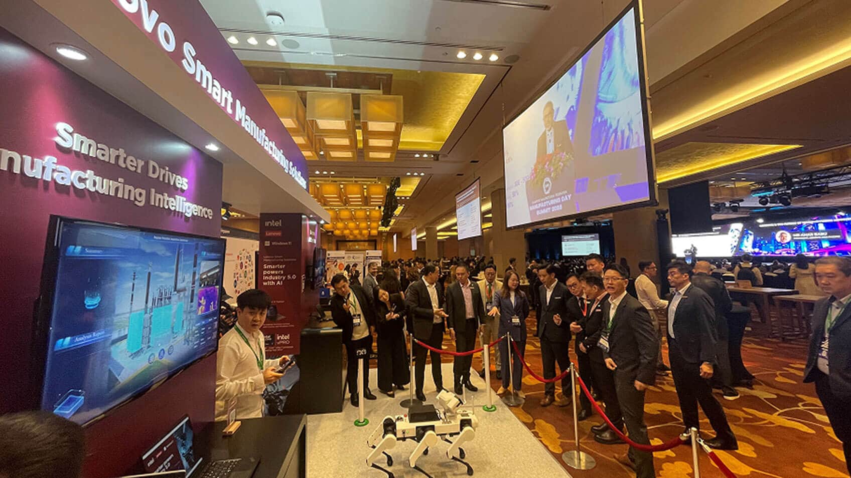 Conference attendees standing behind a rope as a person demonstrates a robot’s capabilities.