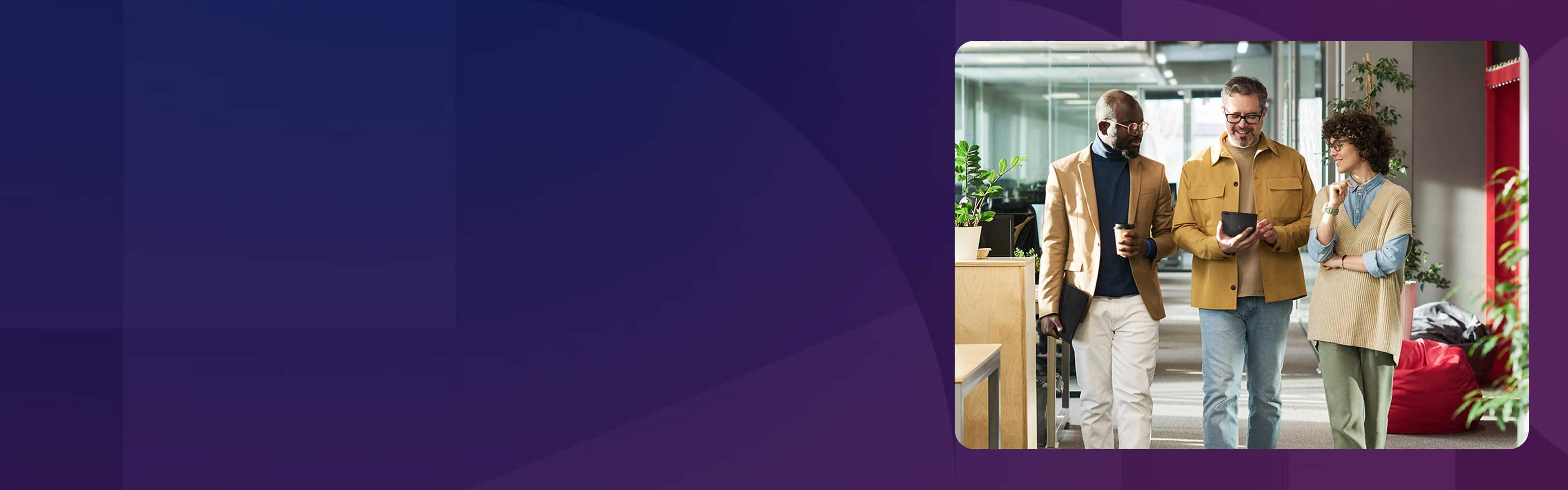 Three colleagues walking through an office, with the man in the middle holding a tablet. 