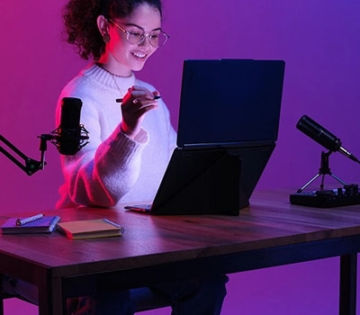 Молодой человек работает за столом с планшетом Yoga Book. Крышка устройства раскрыта на 180 градусов.