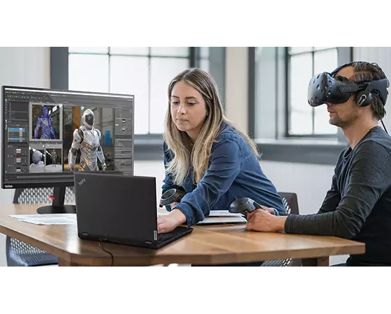 Zwei Personen an einem Schreibtisch mit Controllern, einem Lenovo ThinkPad P15 Gen 2 Notebook, ein Monitor zeigt ein Virtual-Reality-Bild und eine Person trägt eine AR/VR-Brille.