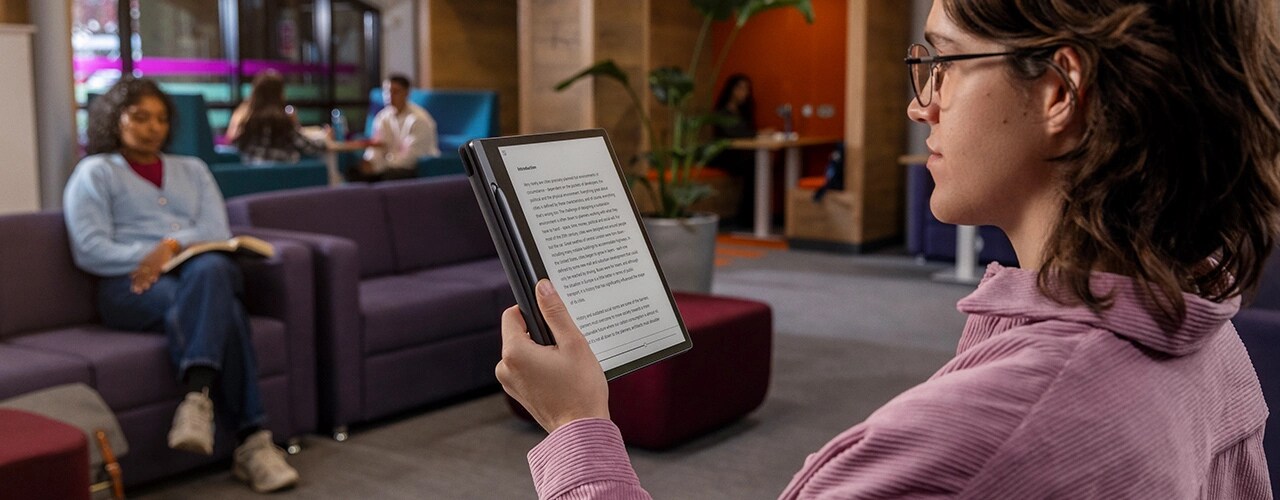 Two students in a cafe with Lenovo Smart Paper E-Ink reader laid flat, with one student making notes on screen with Lenovo Smart Pen