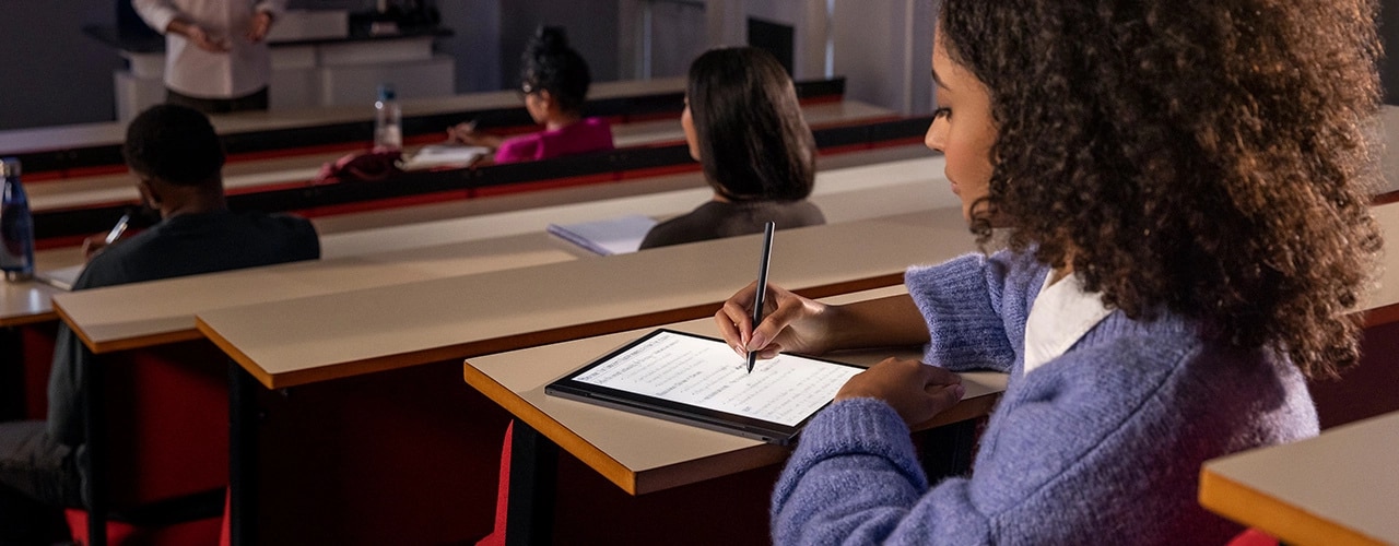 Student in a lecture with Lenovo Smart Paper E-Ink reader laid flat, making notes on screen with Lenovo Smart Pen