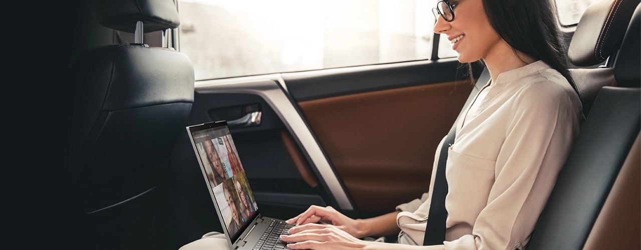 A woman in the backseat of a car with a video call on the Lenovo ThinkPad X1 Yoga Gen 8 2-in-1 laptop.